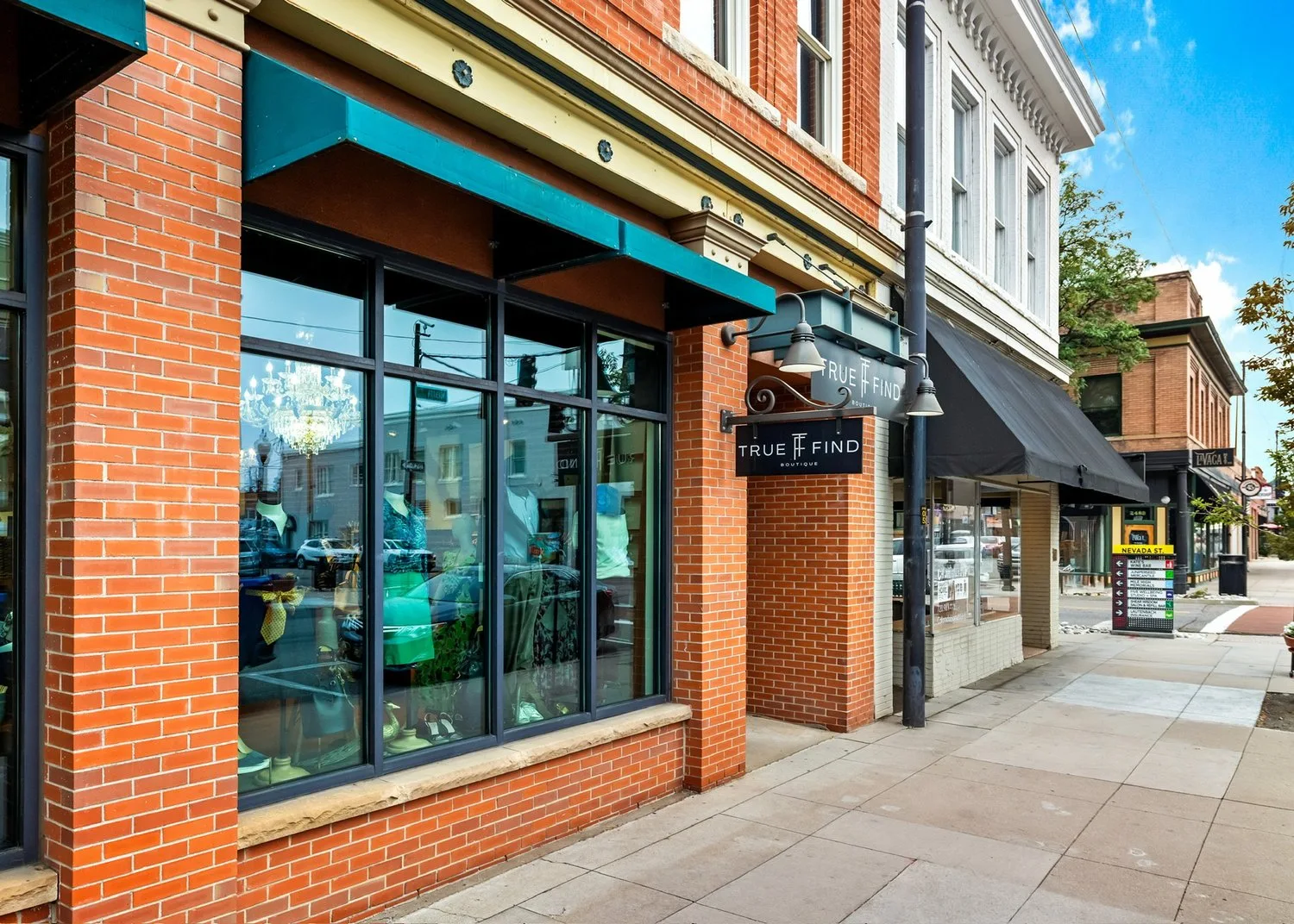 True Find Boutique storefront with red brick facade and black-framed windows on street
